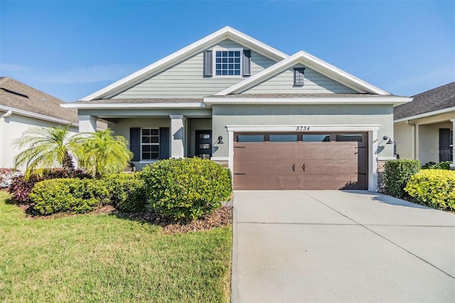 view of front of house featuring an attached garage, driveway, a front lawn, and stucco siding