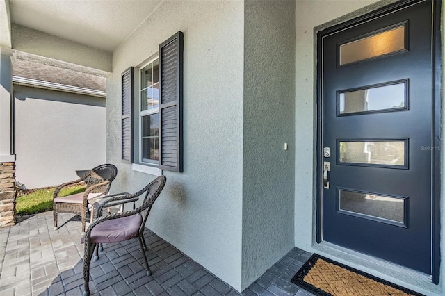 entrance to property featuring a porch and stucco siding