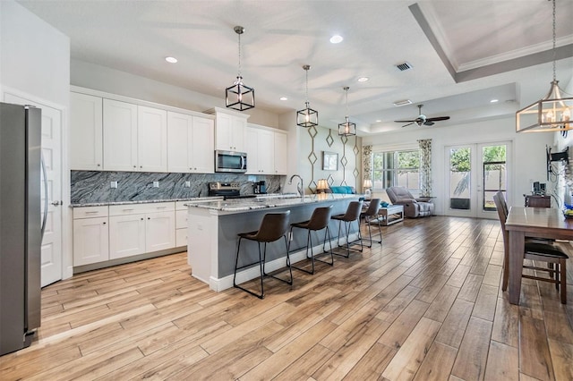 kitchen featuring stainless steel appliances, open floor plan, visible vents, and backsplash