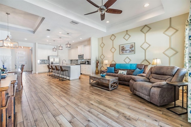 living room featuring ornamental molding, a tray ceiling, and visible vents