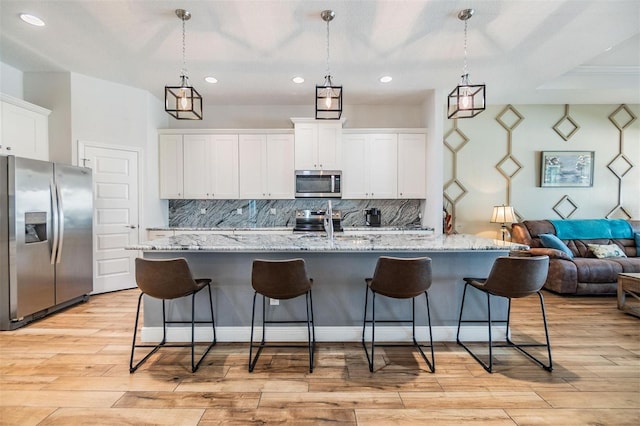 kitchen with white cabinets, a kitchen bar, appliances with stainless steel finishes, and open floor plan