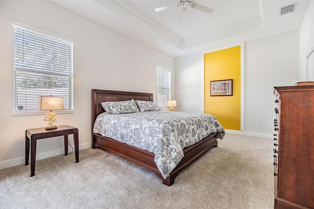bedroom with a tray ceiling, crown molding, light colored carpet, visible vents, and baseboards