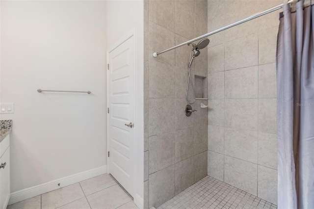 full bathroom featuring tile patterned flooring, tiled shower, vanity, and baseboards