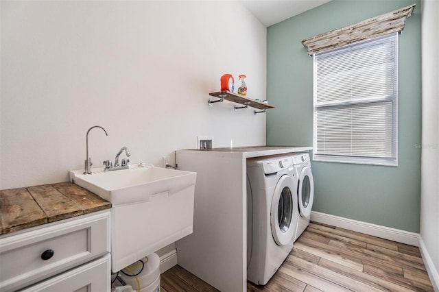 washroom with laundry area, baseboards, light wood-style flooring, independent washer and dryer, and a sink