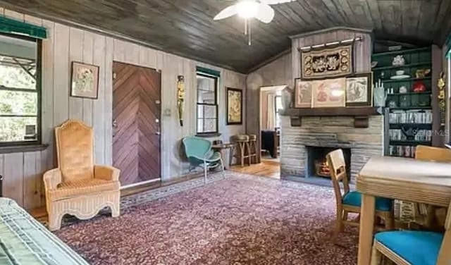 interior space featuring wooden ceiling, a lit fireplace, wooden walls, and vaulted ceiling