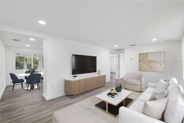 living room with recessed lighting, visible vents, baseboards, and wood finished floors