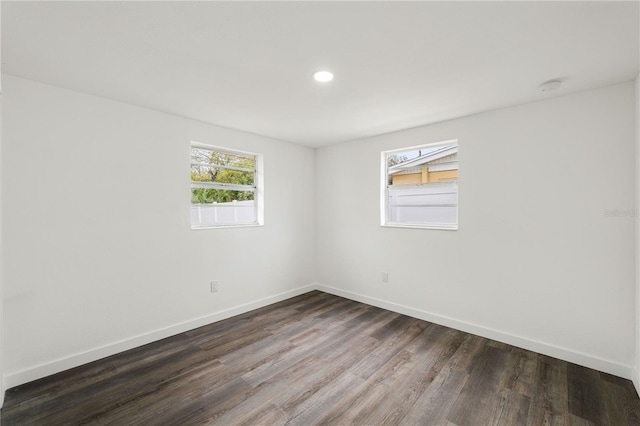 empty room with baseboards, dark wood-type flooring, and recessed lighting