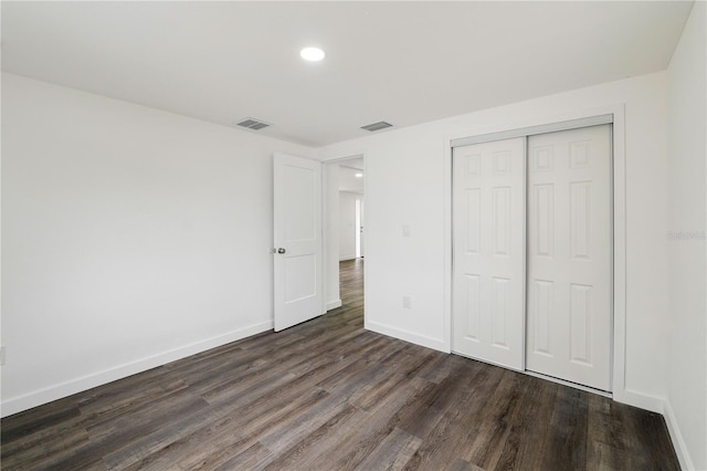 unfurnished bedroom featuring baseboards, visible vents, dark wood finished floors, and a closet