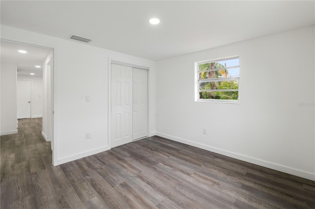 unfurnished bedroom featuring dark wood-style floors, recessed lighting, a closet, visible vents, and baseboards