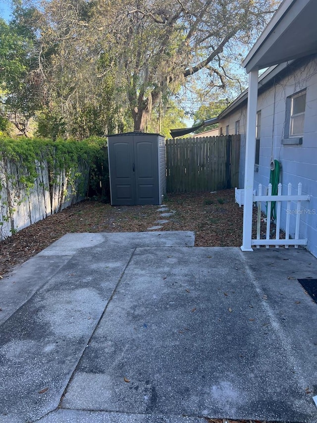 view of patio with fence, an outdoor structure, and a shed