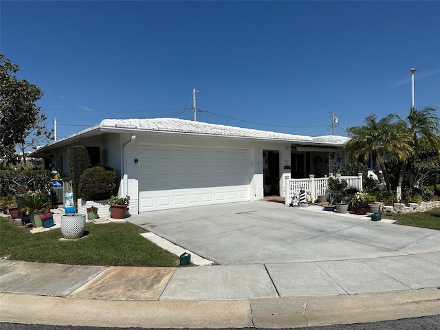 ranch-style home with a porch, a garage, a tile roof, concrete driveway, and stucco siding