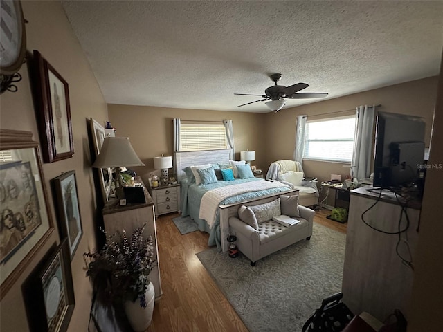 bedroom with ceiling fan, a textured ceiling, and wood finished floors