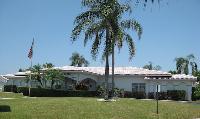 mediterranean / spanish house featuring a tiled roof, a front lawn, and stucco siding