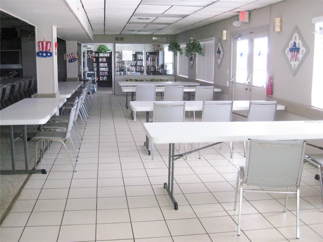 dining area featuring light tile patterned flooring and a paneled ceiling