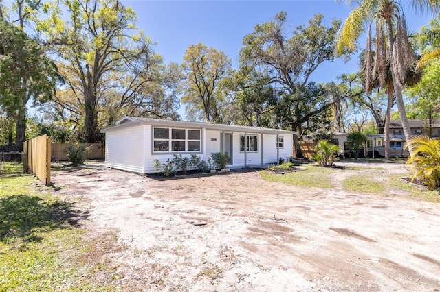 ranch-style home featuring driveway and fence