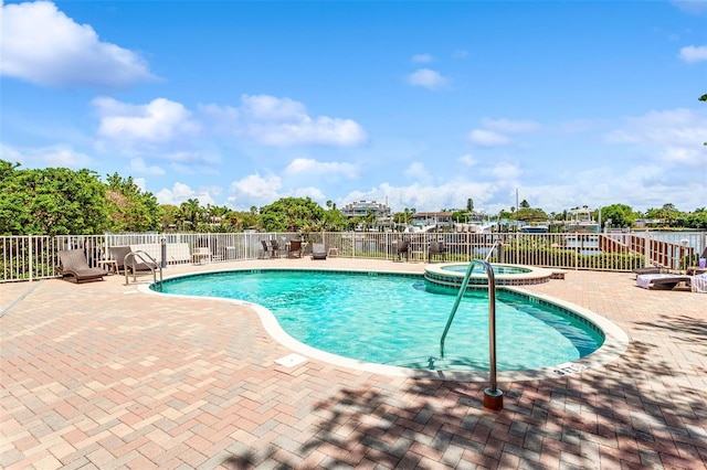 view of pool with a pool with connected hot tub, fence, and a patio