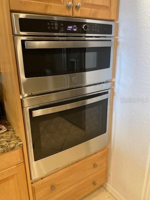 3805 Gulf Blvd Unit 404, St Pete Beach, FL 33706 - kitchen with double oven, light stone countertops, and baseboards