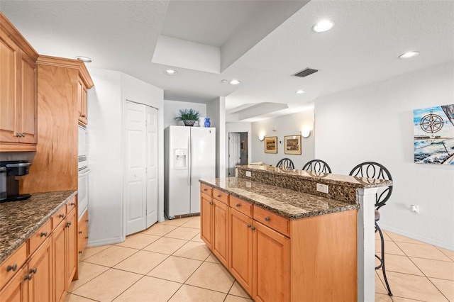 3805 Gulf Blvd Unit 404, St Pete Beach, FL 33706 - kitchen with white appliances, a breakfast bar, light tile patterned floors, a center island, and recessed lighting