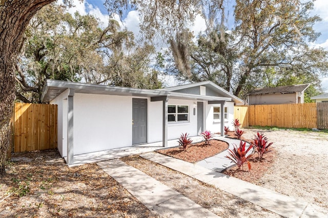 view of front facade featuring covered porch, fence, and stucco siding