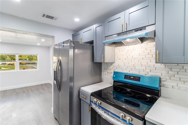 kitchen featuring light wood finished floors, visible vents, backsplash, appliances with stainless steel finishes, and under cabinet range hood