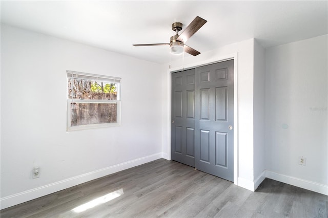 unfurnished bedroom featuring ceiling fan, baseboards, a closet, and wood finished floors