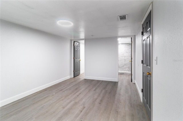 unfurnished room with light wood-style floors, visible vents, and baseboards