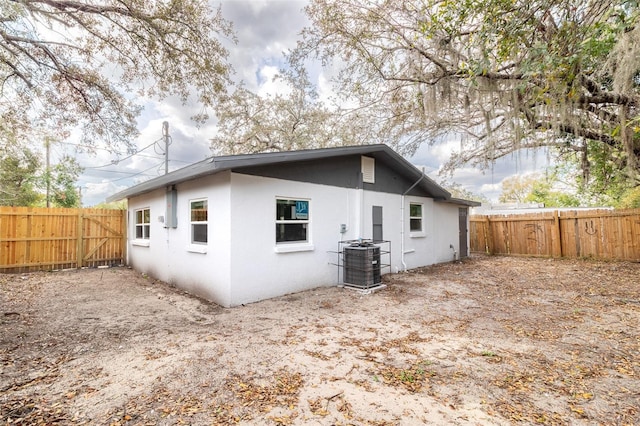 rear view of property with central AC, a fenced backyard, and stucco siding