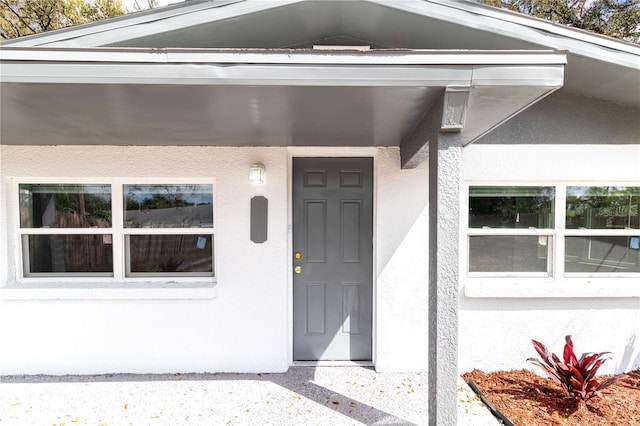 doorway to property featuring stucco siding