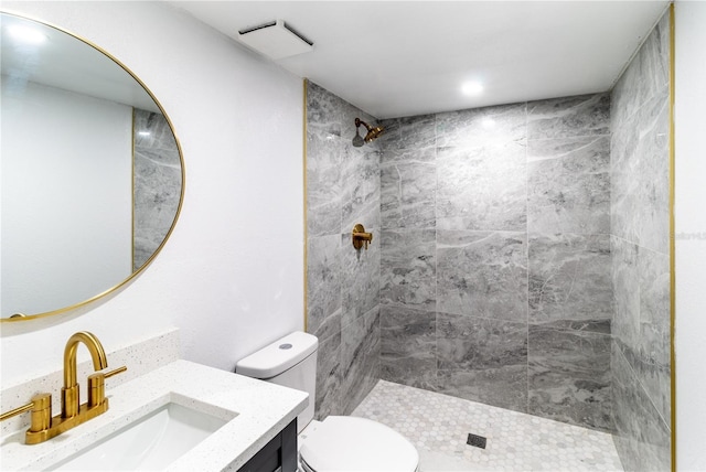 bathroom featuring visible vents, a tile shower, vanity, and toilet