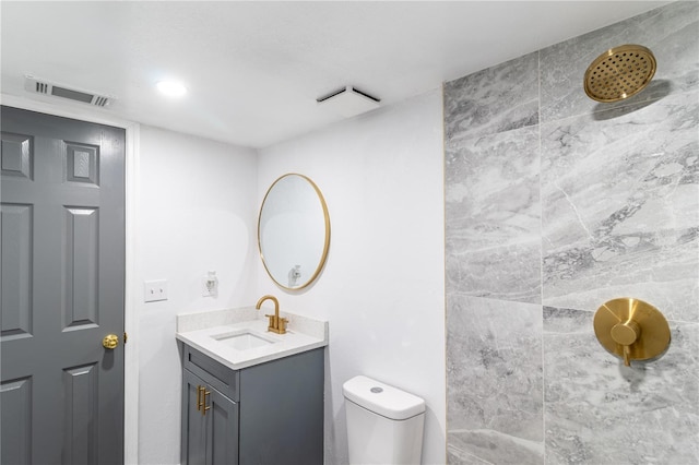 bathroom featuring visible vents, vanity, toilet, and tiled shower