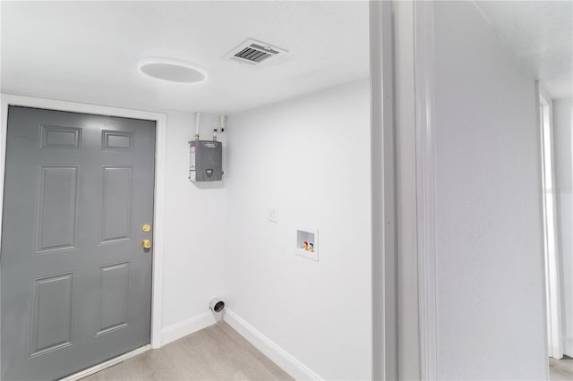 clothes washing area with hookup for a washing machine, laundry area, visible vents, baseboards, and light wood finished floors