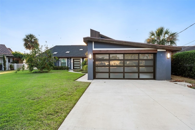 modern home featuring an attached garage, a front lawn, concrete driveway, and stucco siding