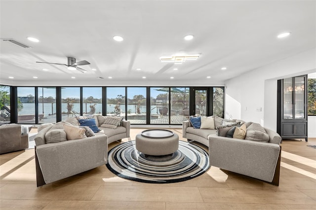 living area featuring a ceiling fan, recessed lighting, visible vents, and a water view