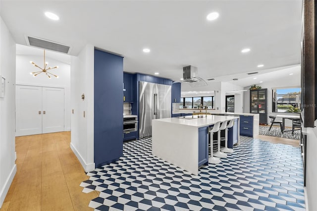 kitchen featuring light countertops, visible vents, a kitchen island, blue cabinets, and high end refrigerator