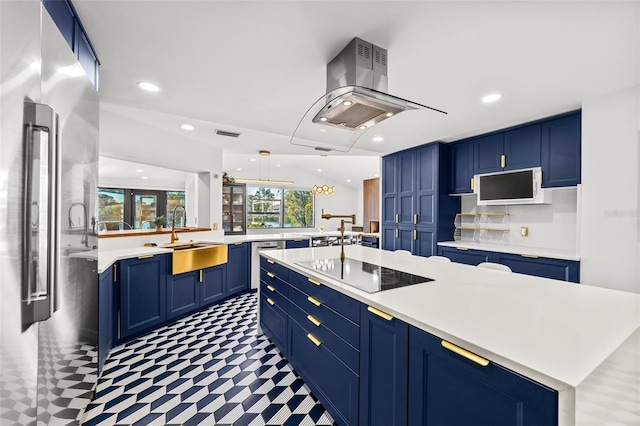 kitchen with island exhaust hood, blue cabinetry, light countertops, appliances with stainless steel finishes, and a sink