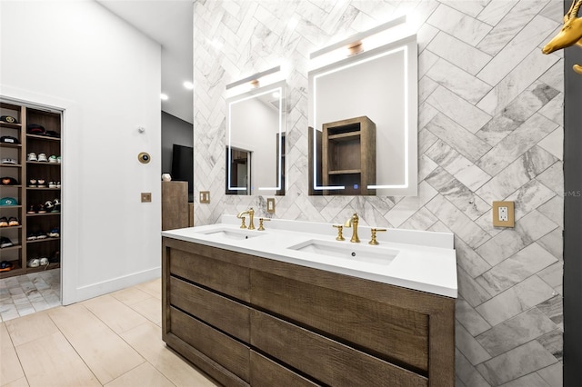 full bathroom featuring a walk in closet, a sink, tile walls, and double vanity