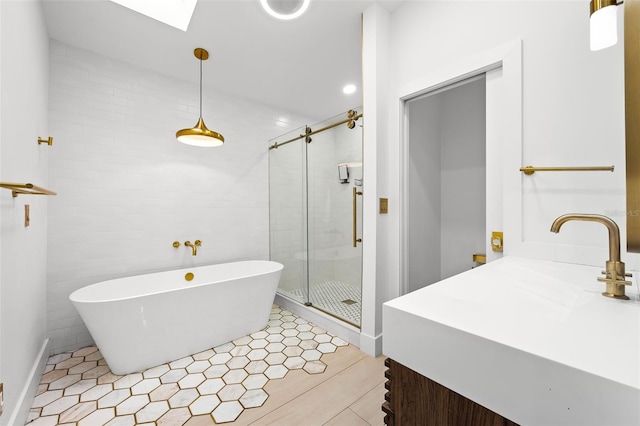 bathroom with a stall shower, a skylight, a soaking tub, and tile walls