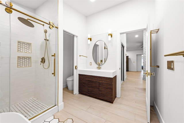 full bathroom featuring vanity, a shower stall, toilet, and baseboards