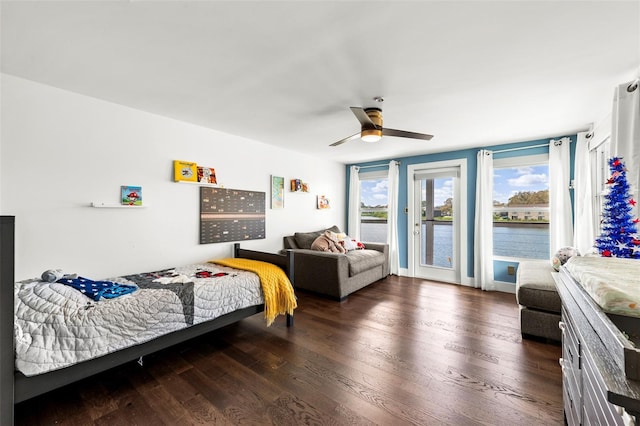 bedroom with a ceiling fan, access to outside, a water view, and wood finished floors