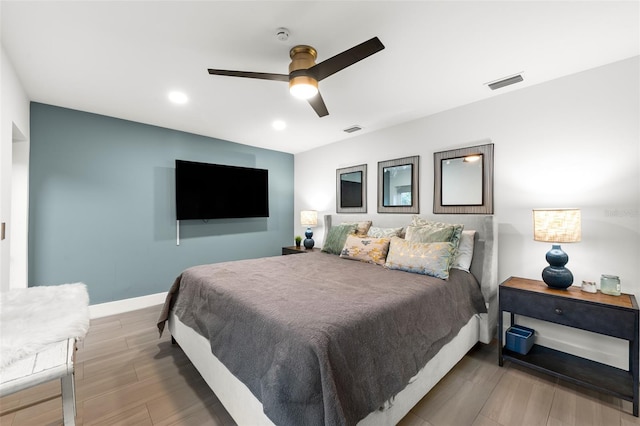 bedroom with baseboards, visible vents, ceiling fan, and wood finished floors