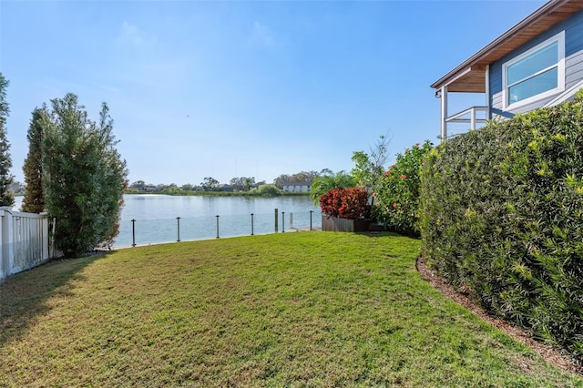 view of yard featuring a water view, fence, and a boat dock