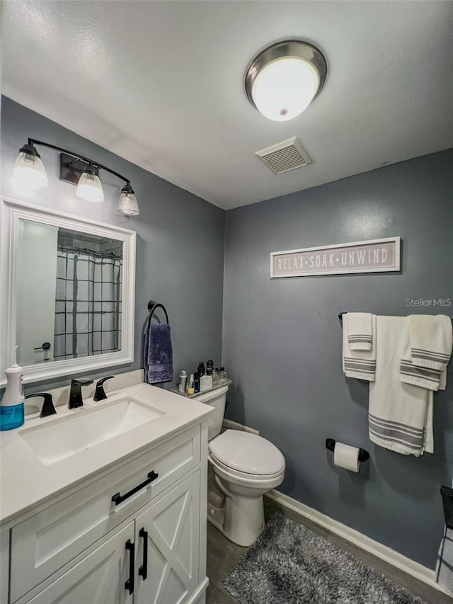 bathroom with visible vents, toilet, vanity, a shower with curtain, and baseboards