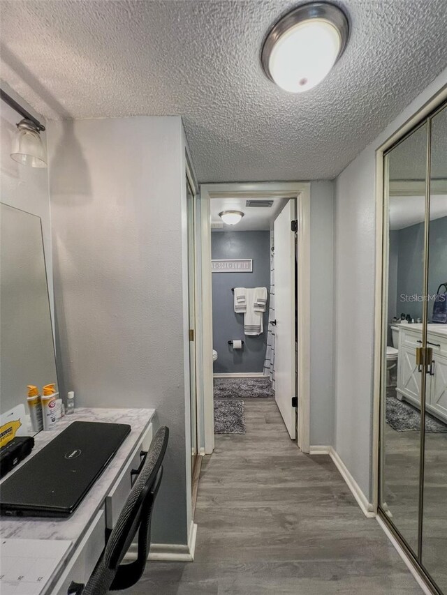 bathroom featuring baseboards, a textured ceiling, toilet, and wood finished floors