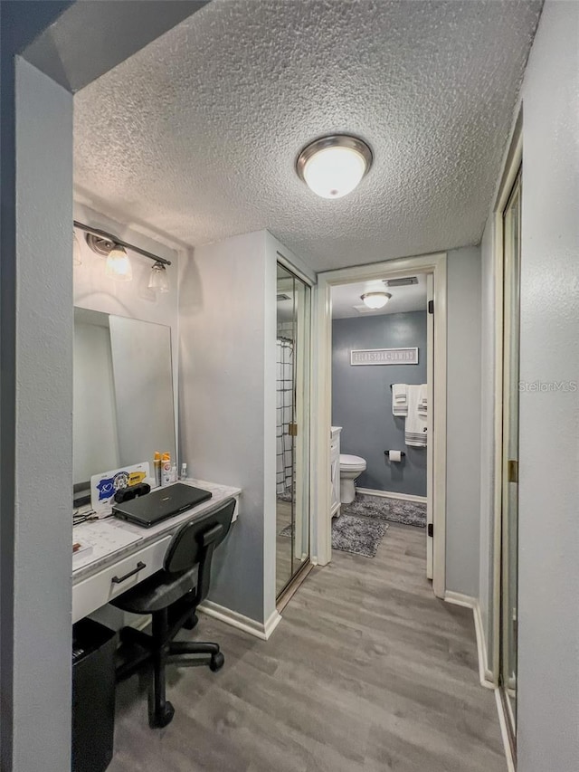 office featuring a textured ceiling, baseboards, and wood finished floors