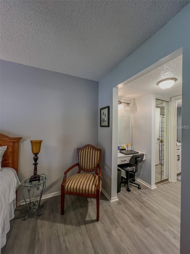 bedroom with a textured ceiling, baseboards, and wood finished floors