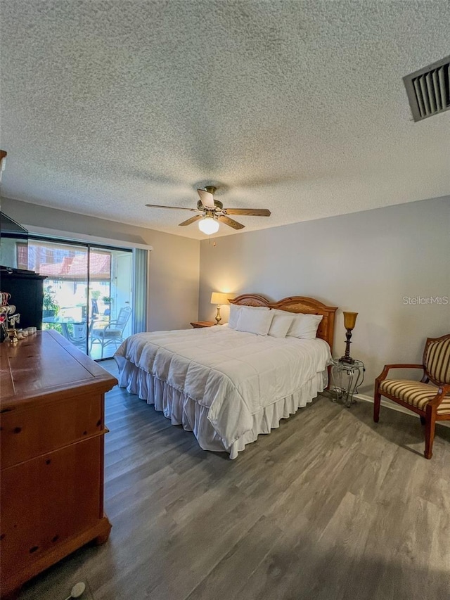 bedroom with ceiling fan, a textured ceiling, wood finished floors, and visible vents