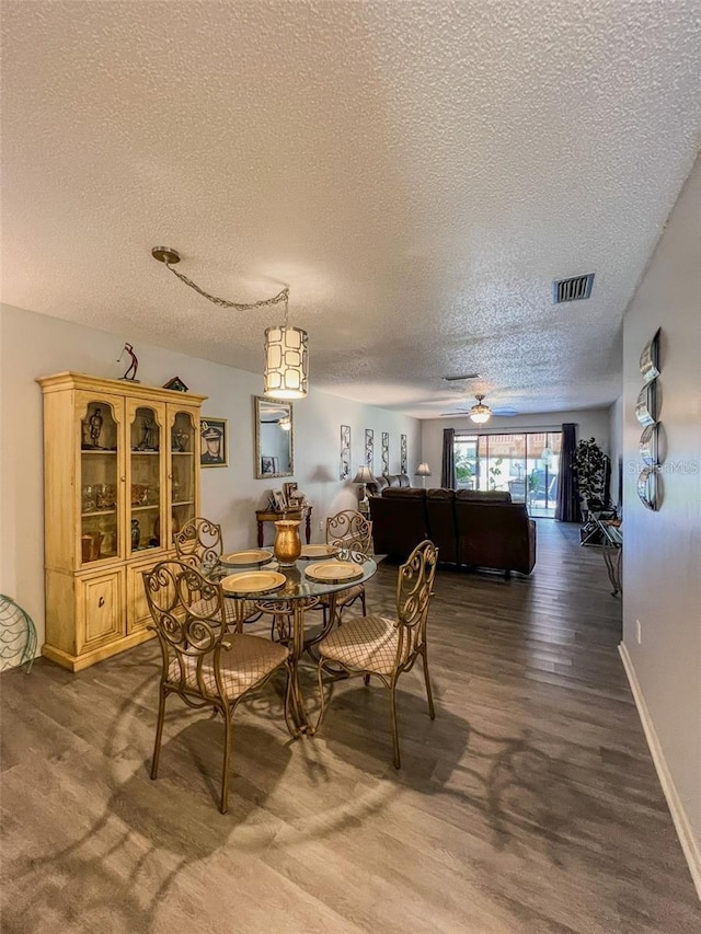 dining space with dark wood-style flooring, visible vents, ceiling fan, a textured ceiling, and baseboards