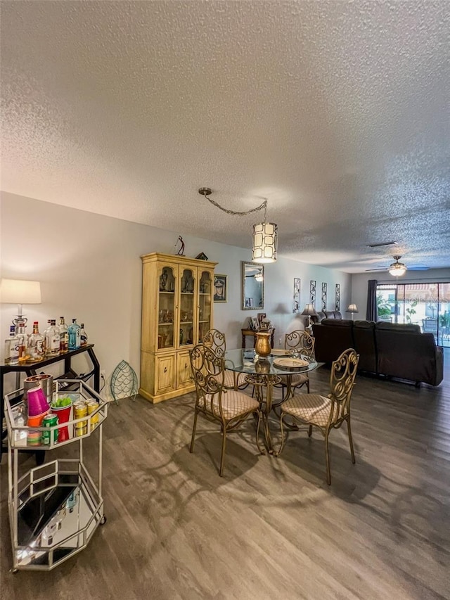 dining area with dark wood-type flooring, ceiling fan, and a textured ceiling