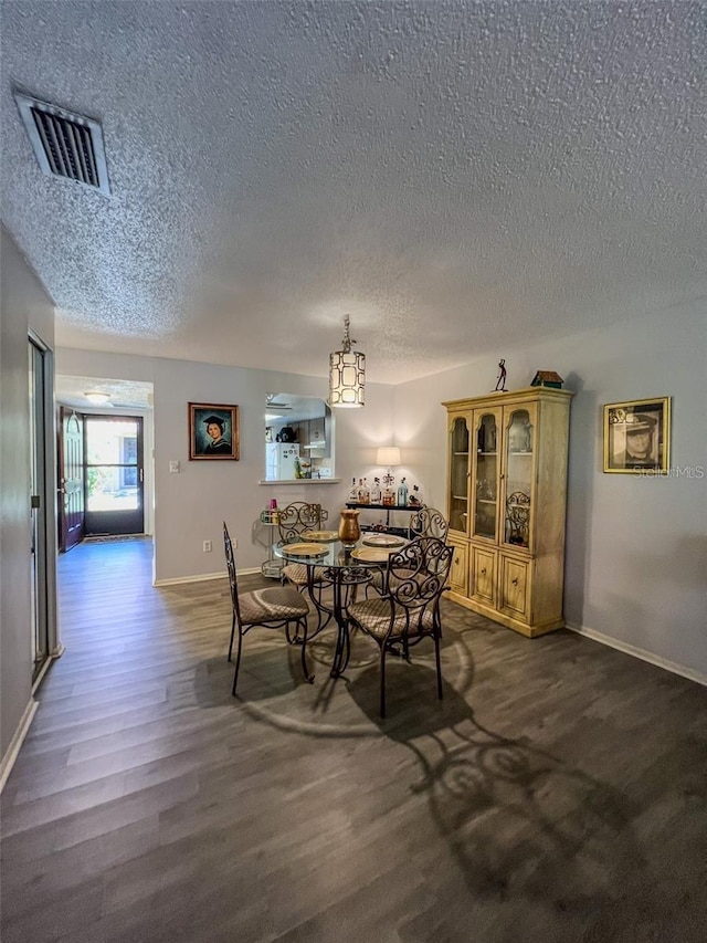 dining area with visible vents, dark wood finished floors, a textured ceiling, and baseboards