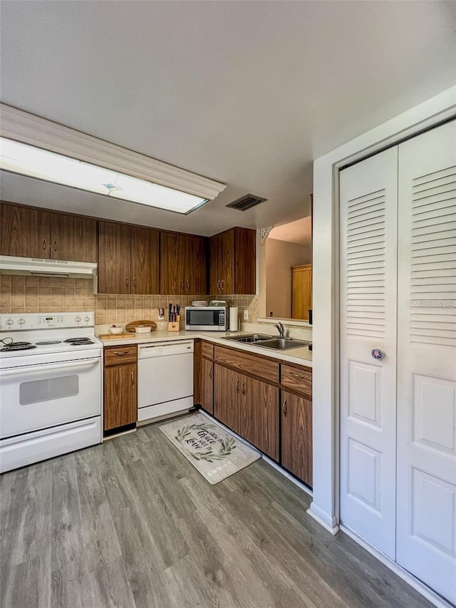 kitchen featuring white appliances, visible vents, light countertops, under cabinet range hood, and a sink